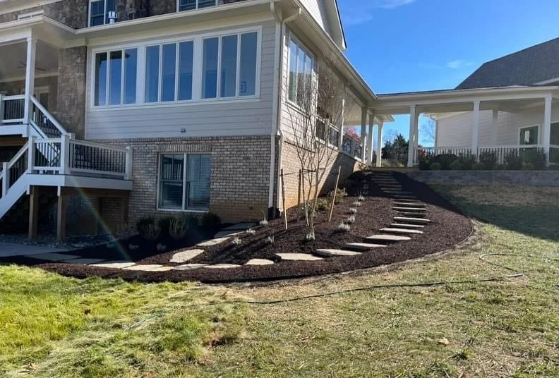 Morales Landscaping — full backyard transformation with curving stepping-stone walk, fresh mulch beds, and new plantings on a sloped lot