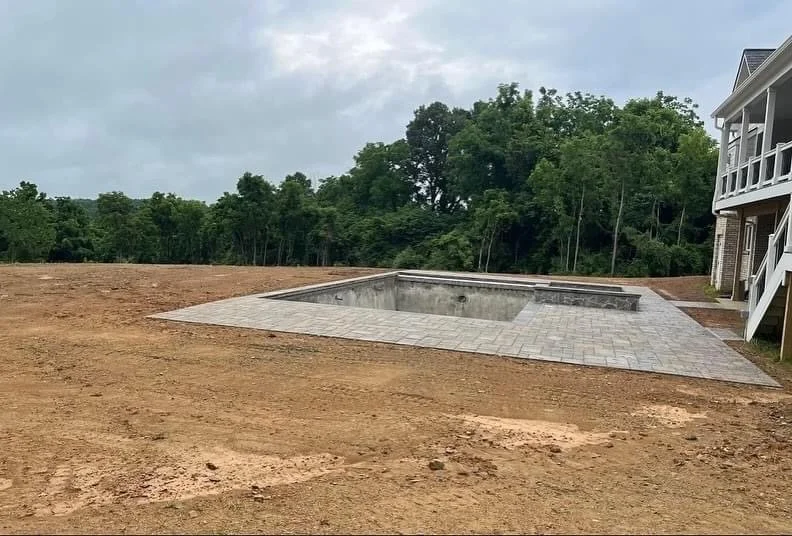 Morales Landscaping — new in-ground pool shell with stone-paver deck installed, regrading around the pool